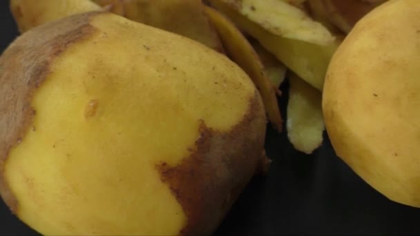 Batatas peladas e casca de batata no fundo preto — Vídeo de Stock