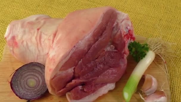 Raw knuckle of pork on wooden cutting board with garlic — Stock Video