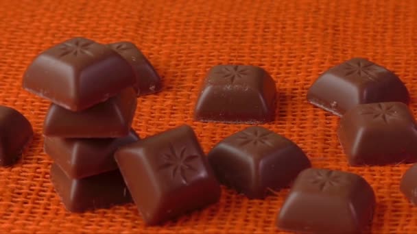 Шоколадные конфеты на фоне апельсина — стоковое видео