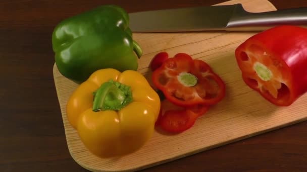 Snijden en voorbereiden van paprika op een snijplank, met inbegrip van rood, geel en groen — Stockvideo