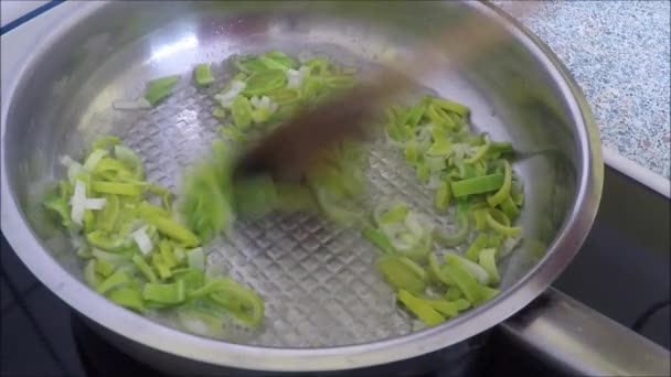 Guisando fatias de alho-porro em uma panela de ato de fritar em uma chapa quente — Vídeo de Stock