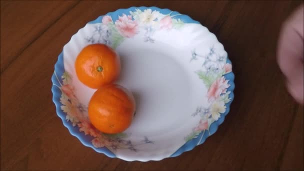 Tangerines on plate on wooden background — Stock Video