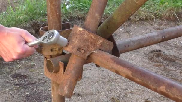 Trabajador con llave inglesa en la mano construye andamio de hierro — Vídeo de stock
