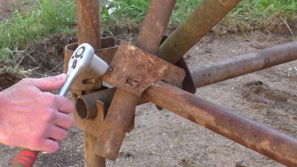 Працівник з гайковим ключем в руці будує залізний риштування — стокове відео