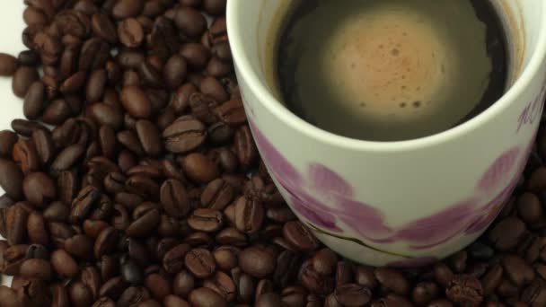 Taza de café blanco con café y alrededor de la taza se encuentra granos de café — Vídeo de stock