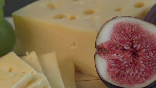 Yellow cheese and fresh figs on the wooden cutting board — Stock Video