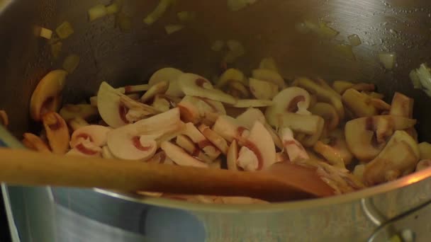 Champignons worden gebakken in een pan met een houten lepel — Stockvideo