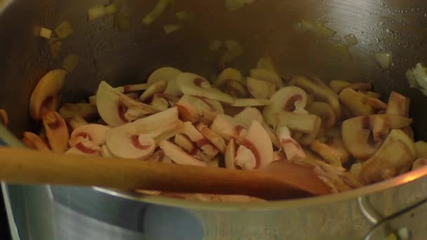 Setas salteadas en una sartén con una cuchara de madera — Vídeos de Stock