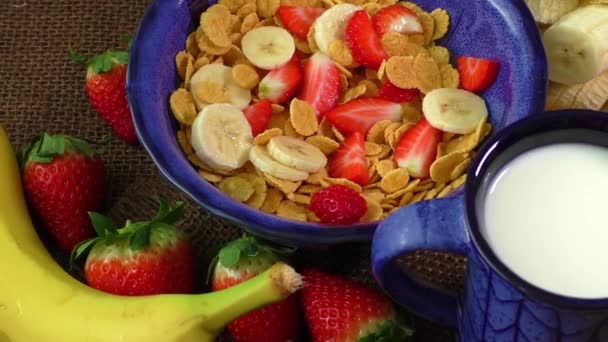 Desayuno saludable. Copos de maíz, fresas frescas, plátano y leche — Vídeo de stock
