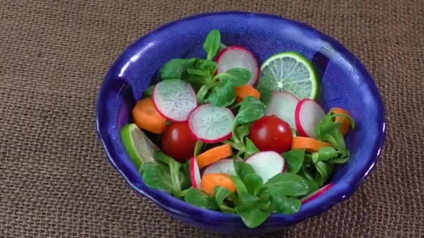 Чаша свіжого овочевого салату на джутовій тканині столу — стокове відео