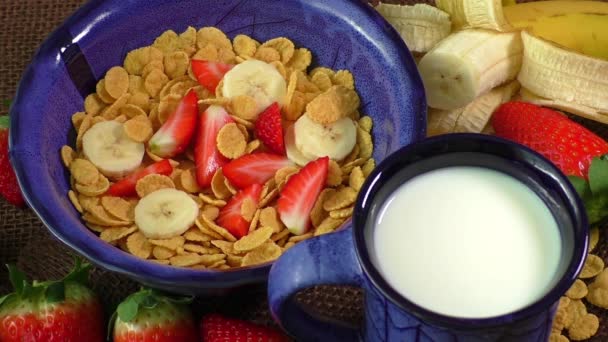 Gezond ontbijt. Cornflakes, melk, verse aardbeien en banaan — Stockvideo