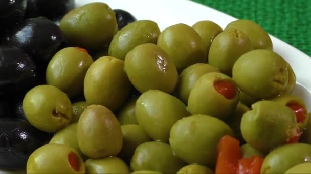 Green and black olives on a white plate — Stock Video
