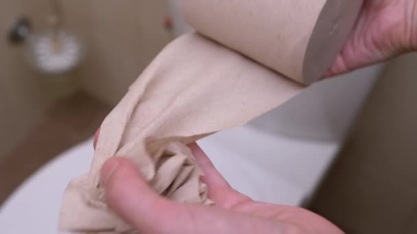 As mãos femininas enrolam e rasgam um pedaço de papel higiênico. Close-up. Movimento lento — Vídeo de Stock