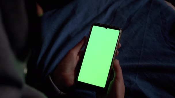 З капюшоном жінка в темних тримає і оглядає смартфон з зеленим сенсорним екраном . — стокове відео