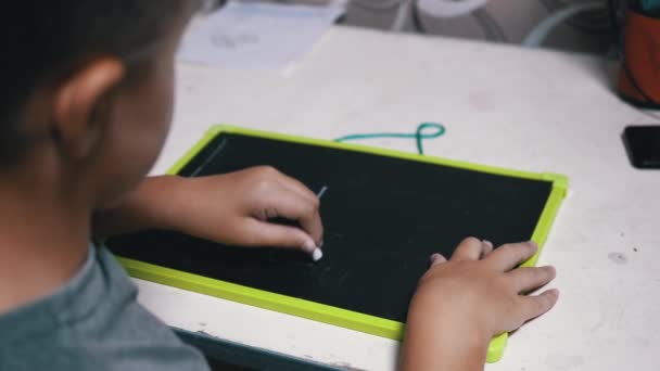 Tehetséges kréta fiú rajzol és ír leveleket egy fa táblára. Online tanulás — Stock videók