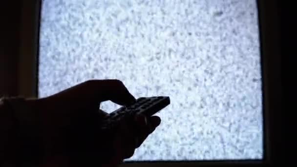 Mano masculina cambia canales con interferencia de ruido de pantalla en la habitación oscura. Retro TV — Vídeos de Stock