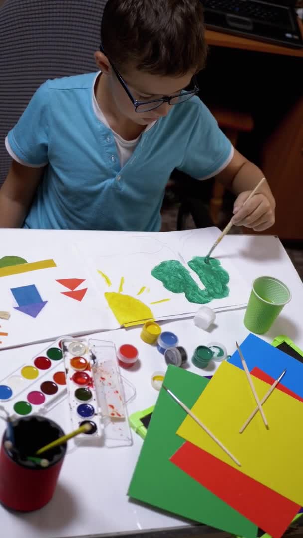 Kind met een penseel in handverven zon met gele verf op wit vel papier — Stockvideo