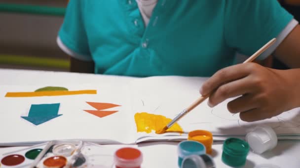 Enfant avec une brosse à la main Peint le soleil avec de la peinture jaune sur une feuille de papier blanche — Video