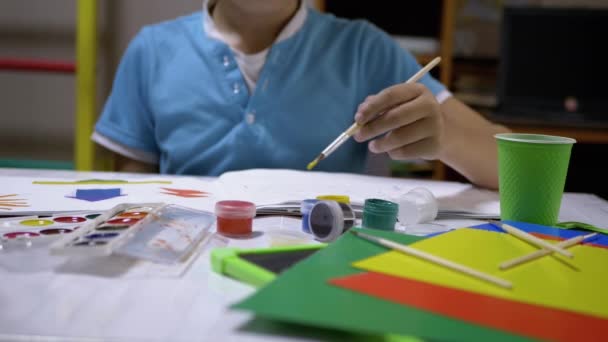 Enfant avec une brosse à la main Peint le soleil avec de la peinture jaune sur une feuille de papier blanche — Video