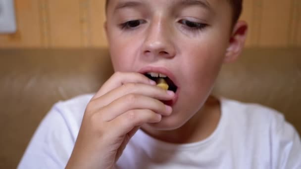 空腹の白人ティーンは手で口の中にクルトンを入れます.男の子はファーストフードを食べる. — ストック動画