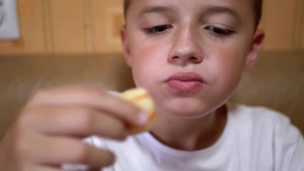 Hambriento caucásico adolescente pone patatas fritas en la boca con la mano. Chico come comida rápida. — Vídeos de Stock