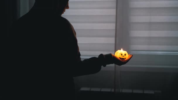 Silhouette di Boy in Hood. Mano tiene una candela di zucca in fiamme in una stanza buia — Video Stock