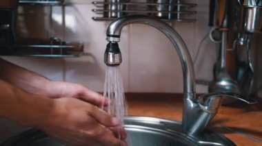 Güçlü bir su püskürtüsünün altında erkek ellerini yıkamak. Sıçrıyor. Su dökülüyor.