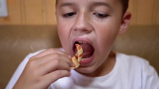 Hungriga kaukasiska Teen Puts Chips i munnen med handen. Boy äter snabbmat. — Stockvideo