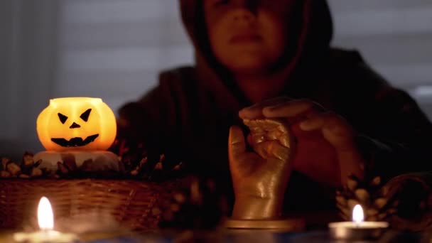 Sciamano ragazzo con in cappuccio esegue rito da candela in camera oscura su halloween — Video Stock