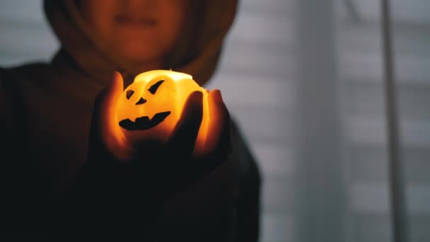 Silhouette de Boy in Hood. Main tient une bougie brûlante à la citrouille dans une pièce sombre — Video