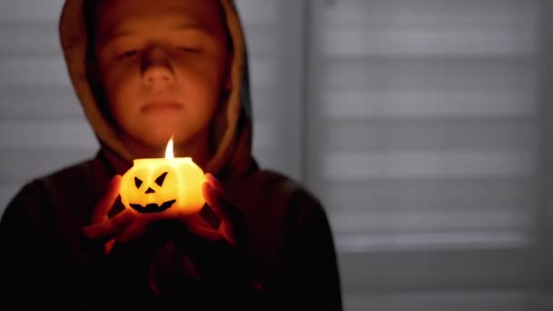 Silhouette di Boy in Hood. Mano tiene una candela di zucca in fiamme in una stanza buia — Video Stock