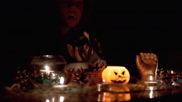 Vampiro menino com capuz joga com aranha por vela no quarto escuro no Halloween — Vídeo de Stock