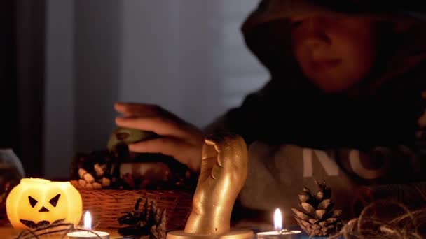 Misterioso ragazzo con in cappuccio gioca con ragno da candela in camera oscura su halloween — Video Stock