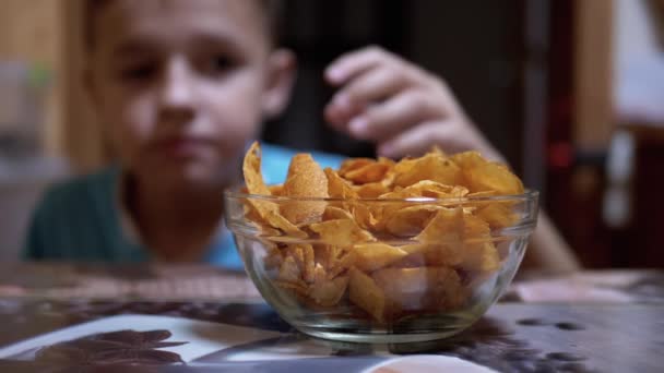 Hongerige tiener steelt chips van tafel in een plaat, terwijl niemand ziet — Stockvideo