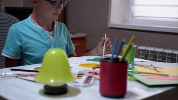 Criança com uma escova na árvore de tintas de mão com tinta verde na folha de papel branca — Vídeo de Stock