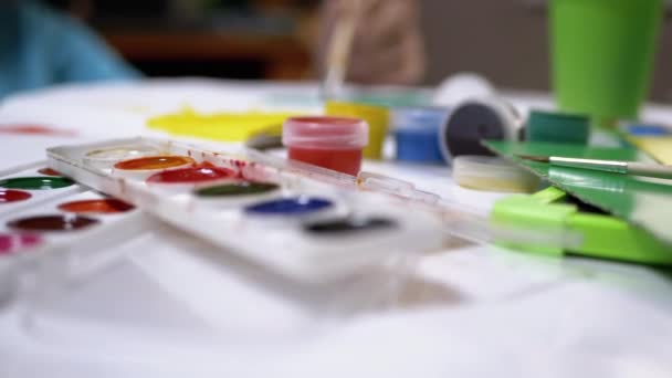 Kid Hand Draws With a Brush Against the Backdrop of a Creative Mess. Watercolor — Stock Video