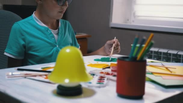 Criança com uma escova na árvore de tintas de mão com tinta verde na folha de papel branca — Vídeo de Stock