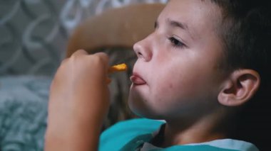 Gülümseyen Aç Çocuk TV izliyor, paketten kraker yiyor. Pasif Dinlenme