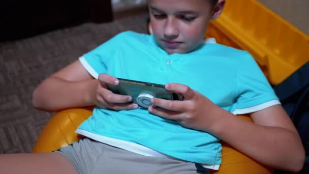 Smiling Boy Sit Παίζει ένα Mobile Game στο Smartphone at Home στο Relaxed State — Αρχείο Βίντεο