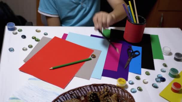 L'enfant met des crayons de couleur sur la table avec les mains. Artiste garçon. Formation en ligne. — Video