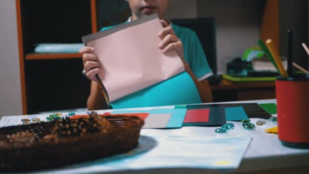 Niño serio con camiseta azul levanta las manos y muestra rosa claro en papel coloreado — Vídeo de stock