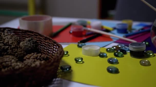 На столе расположены случайные авокарельные краски, карандаши, кисти, цветная бумага — стоковое видео