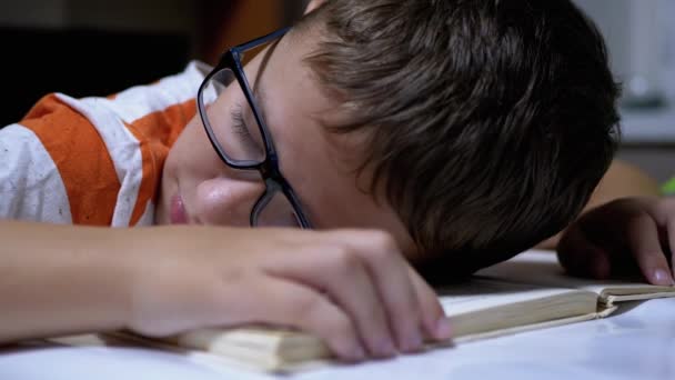 Garçon curieux avec des lunettes tombé endormi sur le livre Lire sur la table. Fatigue, Sommeil — Video