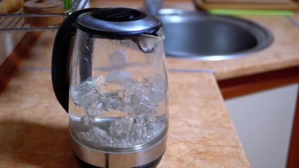 Burbujas en agua caliente hirviendo dentro de vidrio hervidor eléctrico con luz de neón brillante — Vídeos de Stock