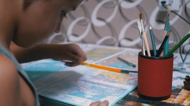 Schoolboy γράφει με το αριστερό χέρι στο σημειωματάριο, χρησιμοποιώντας λαβή, μολύβι. Κοντινό πλάνο — Αρχείο Βίντεο