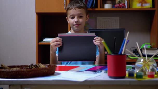 Serious Boy en camiseta azul levanta las manos y muestra negro sobre papel coloreado — Vídeo de stock