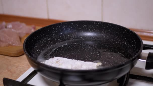 Vrouwelijke Hand legt paneerkip op hete koekenpan. Vlees koken — Stockvideo