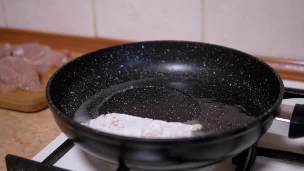 Weibliche Hand legt panierte Hühnerkoteletts auf heiße Pfanne. Fleisch kochen — Stockvideo