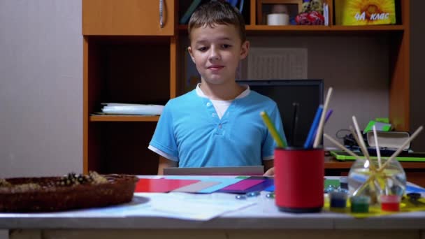 Seriös pojke i blå T-shirt höjer händer och visar rosa på färgat papper — Stockvideo