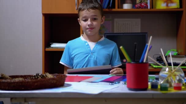 Poważny chłopiec w niebieskiej koszulce podnosi ręce i pokazuje czarny na kolorowym papierze — Wideo stockowe